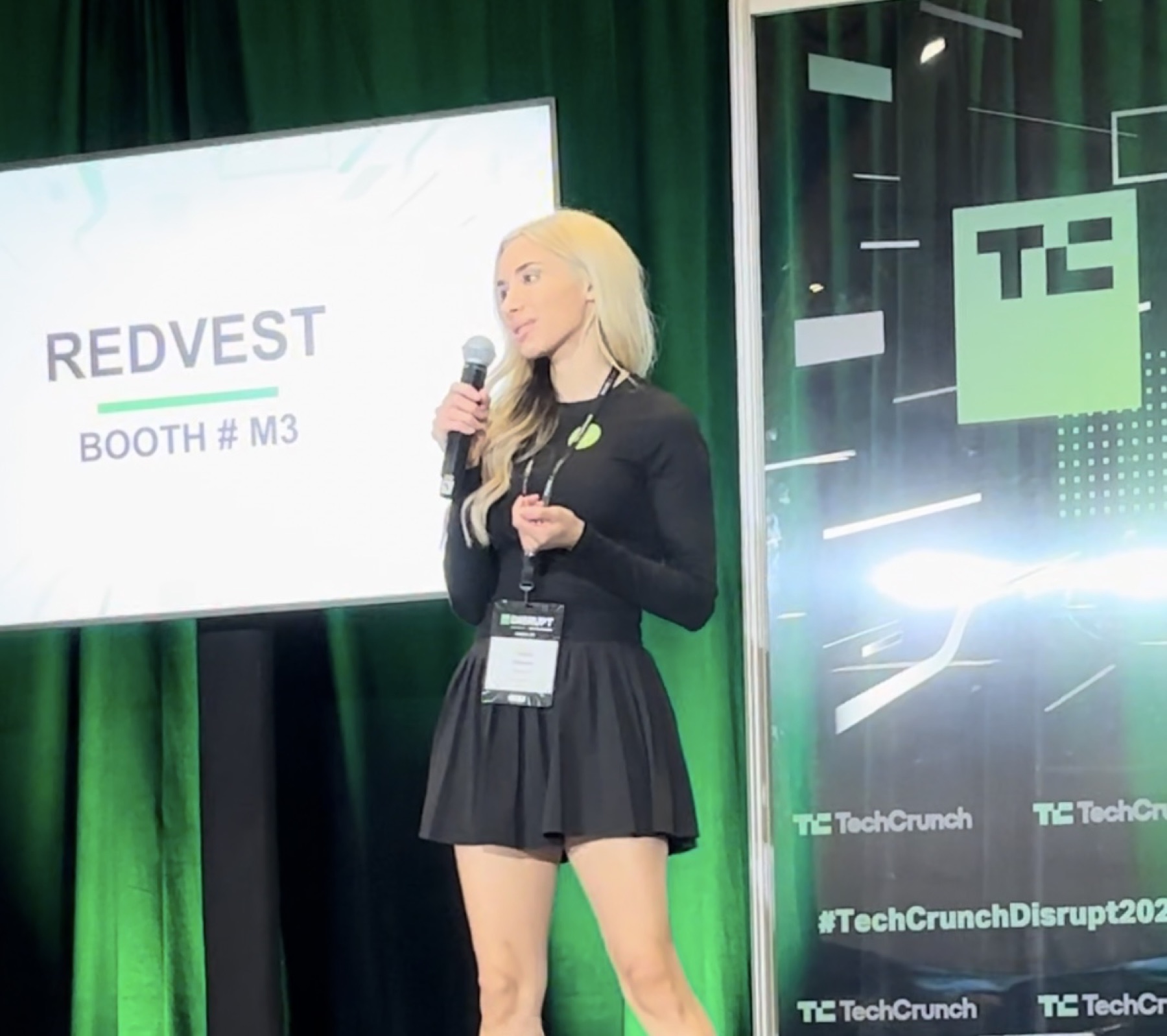 Redvest founder Anya Ozmen presenting beside the TechCrunch Disrupt and Redvest booth M3 displays